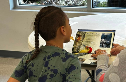 Older child reading with a tutor who is out of frame.